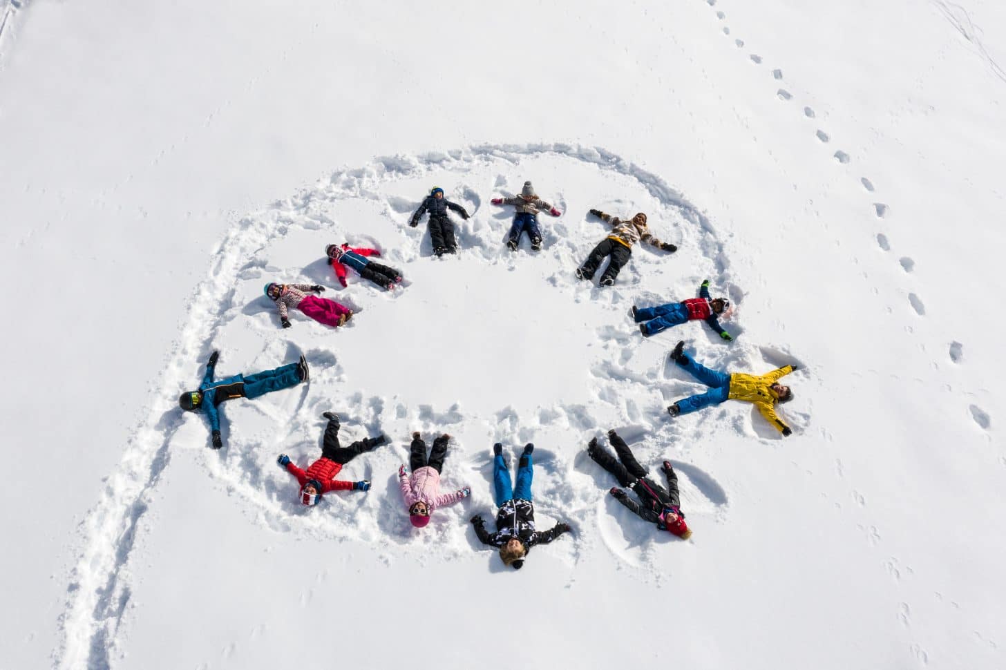 Un groupe d'enfants font la ronde dans la neige en station de ski